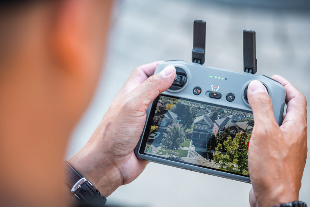 A close up hands holding a drone taking a photo of a real estate listing